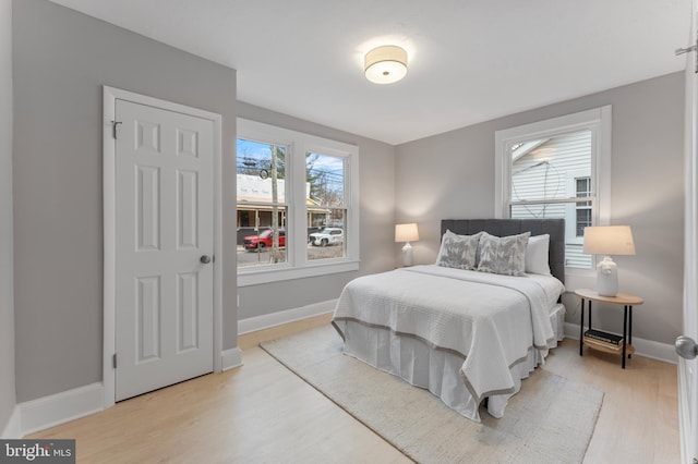 bedroom featuring light wood-style flooring, multiple windows, and baseboards