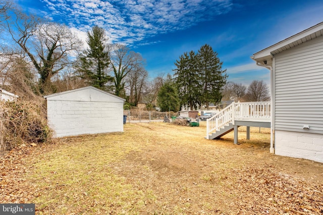 view of yard with an outbuilding, fence, a wooden deck, and stairs