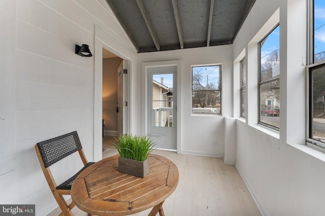 sunroom / solarium featuring vaulted ceiling with beams