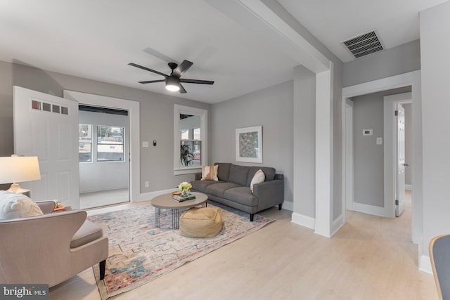 living room featuring ceiling fan, wood finished floors, visible vents, and baseboards