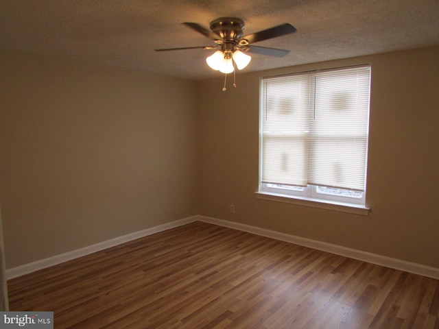 empty room featuring a textured ceiling, wood finished floors, a ceiling fan, and baseboards