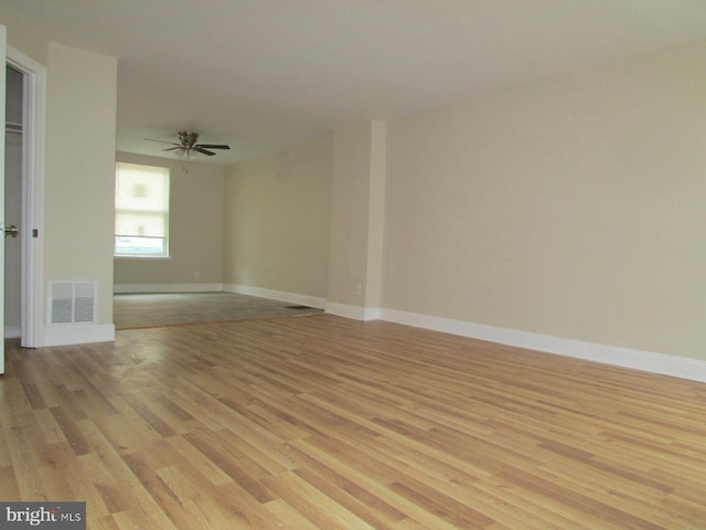 empty room featuring light wood-type flooring, baseboards, visible vents, and ceiling fan