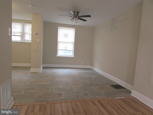 unfurnished room with a wealth of natural light, visible vents, and wood finished floors