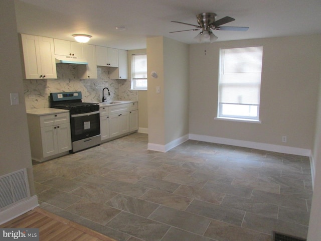 kitchen featuring stainless steel gas range oven, light countertops, under cabinet range hood, white cabinetry, and backsplash