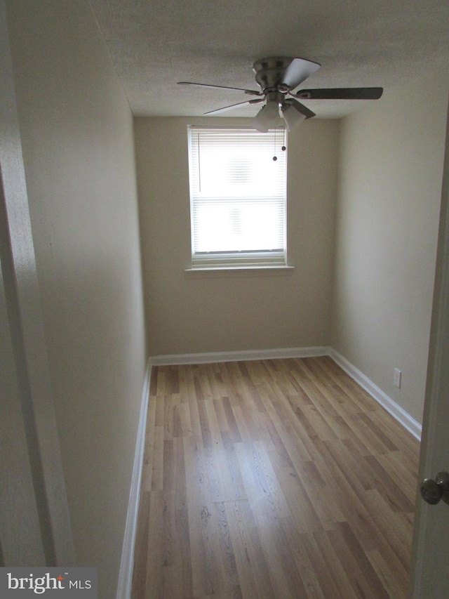 empty room featuring a ceiling fan, a textured ceiling, baseboards, and wood finished floors