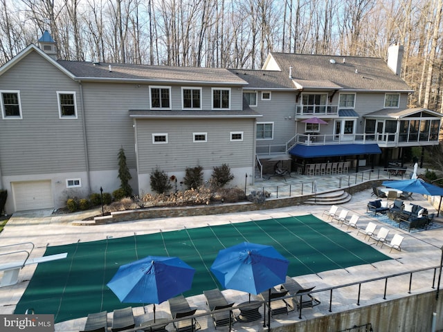 back of property with a patio area, fence, and a covered pool