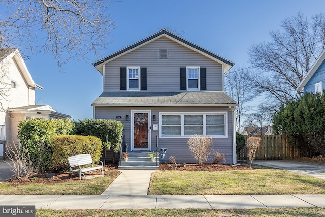 traditional-style house featuring a front lawn and fence