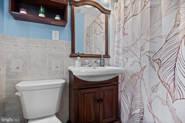 bathroom with vanity, tile walls, and toilet