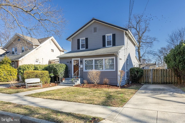 traditional-style house with a gate, a front yard, and fence