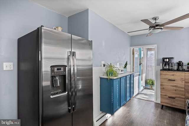 kitchen with blue cabinets, a ceiling fan, a baseboard heating unit, wood finished floors, and stainless steel fridge with ice dispenser