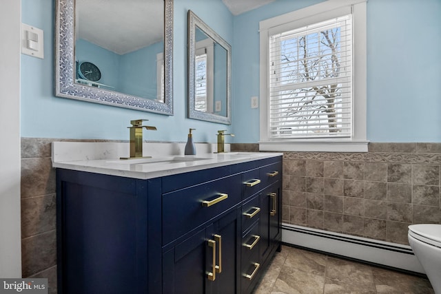 bathroom featuring tile walls, toilet, baseboard heating, and a sink