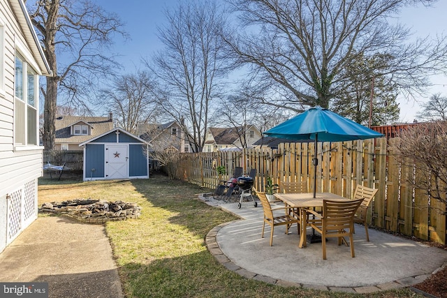 view of yard featuring an outbuilding, a fenced backyard, a storage shed, and a patio area