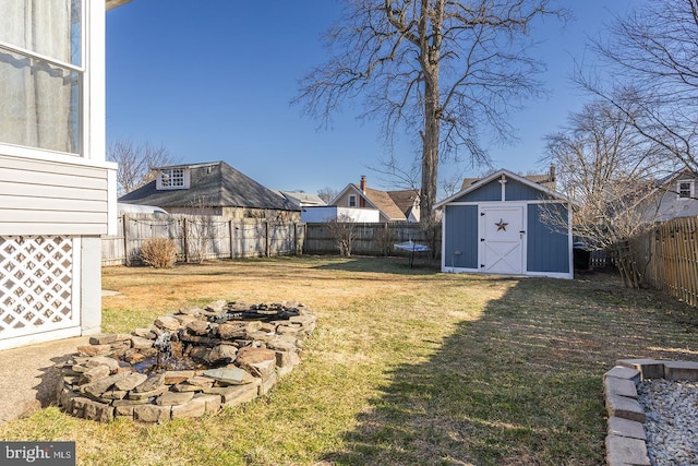 view of yard featuring a fenced backyard, an outdoor structure, a storage unit, a fire pit, and a trampoline