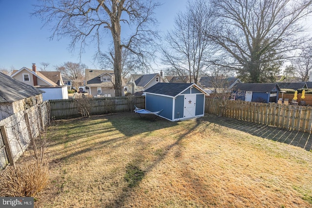 view of yard with a storage unit, a residential view, an outbuilding, and a fenced backyard