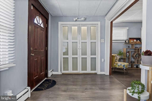 foyer entrance with a baseboard heating unit and wood finished floors