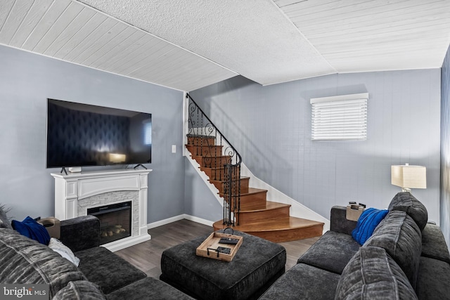 living area with a stone fireplace, stairway, wood finished floors, and baseboards