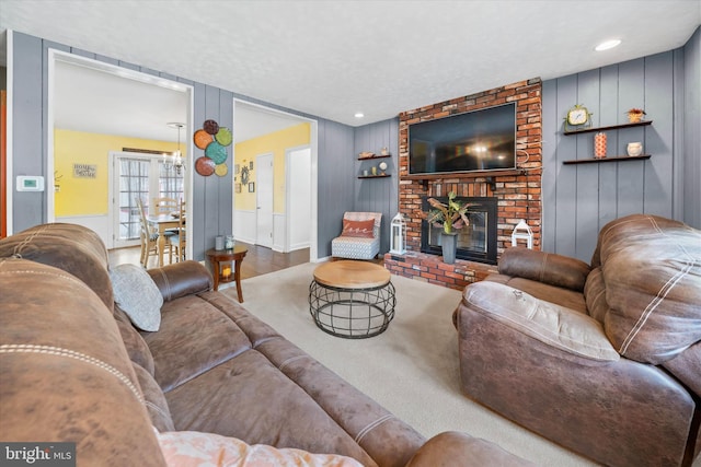 living area with a decorative wall, a brick fireplace, a textured ceiling, and wood finished floors