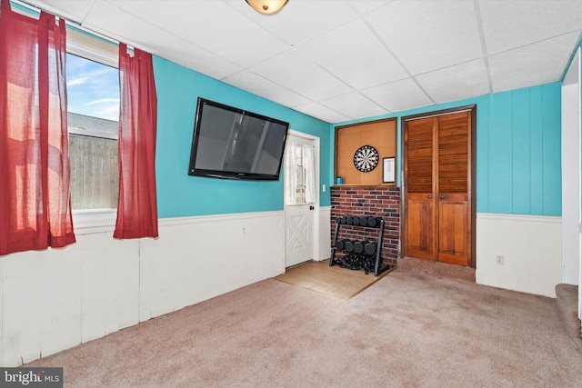 unfurnished living room featuring a wainscoted wall, a paneled ceiling, and carpet flooring