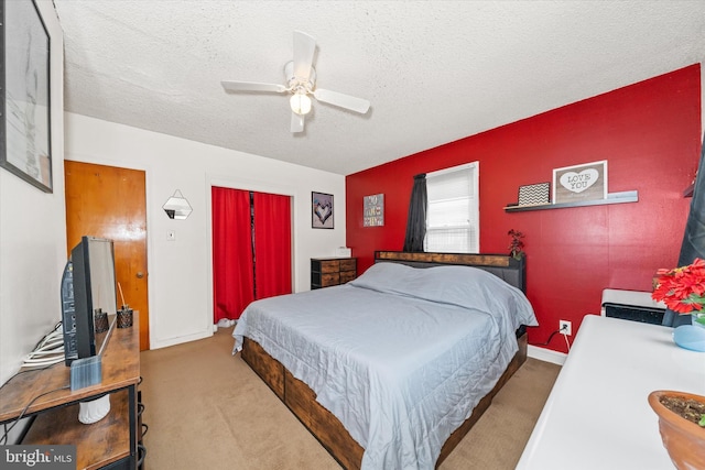 bedroom featuring baseboards, carpet flooring, a closet, a textured ceiling, and a ceiling fan