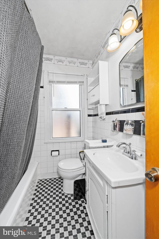 full bath featuring vanity, tile walls, toilet, and shower / bath combo with shower curtain