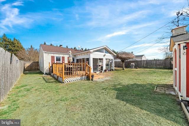 view of yard featuring a deck, a fenced backyard, and a sunroom