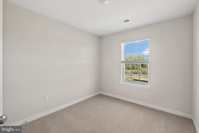 carpeted spare room with visible vents and baseboards