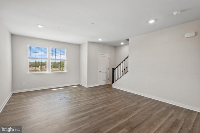 empty room featuring stairs, baseboards, dark wood-type flooring, and recessed lighting