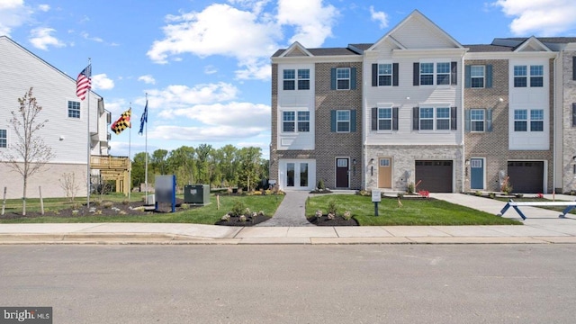 multi unit property featuring a front yard, french doors, an attached garage, and concrete driveway