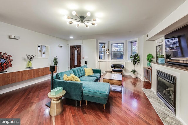 living room featuring a fireplace with flush hearth, baseboards, and wood finished floors