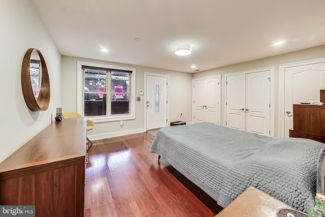 bedroom featuring recessed lighting, dark wood-style flooring, baseboards, and two closets