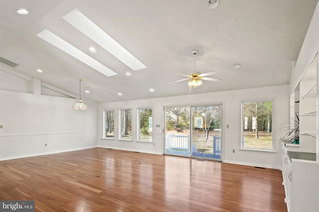 unfurnished living room featuring baseboards, recessed lighting, vaulted ceiling with skylight, wood finished floors, and a ceiling fan