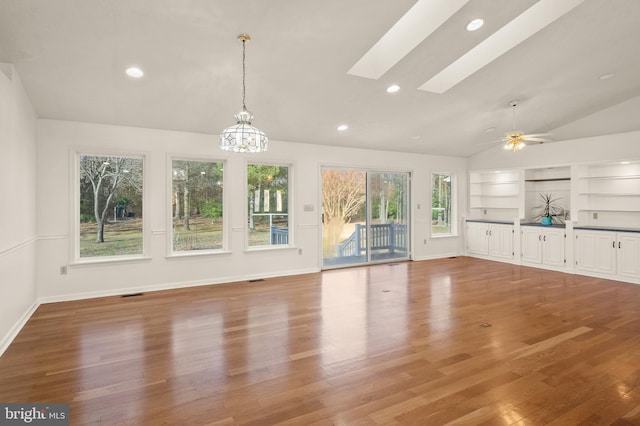 unfurnished living room featuring vaulted ceiling with skylight, recessed lighting, light wood-style floors, and baseboards