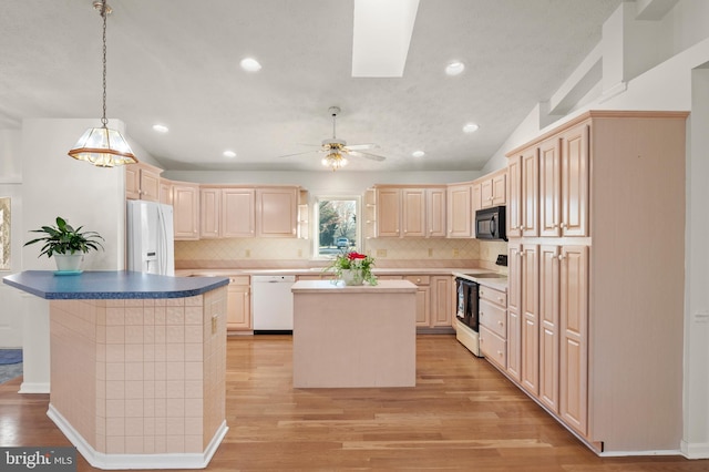 kitchen featuring white appliances, light brown cabinets, light wood-type flooring, and a center island