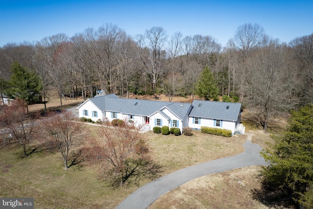 view of front of house with a front yard, a view of trees, and driveway