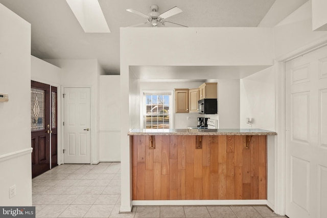 kitchen featuring a breakfast bar, electric range, light tile patterned flooring, and ceiling fan