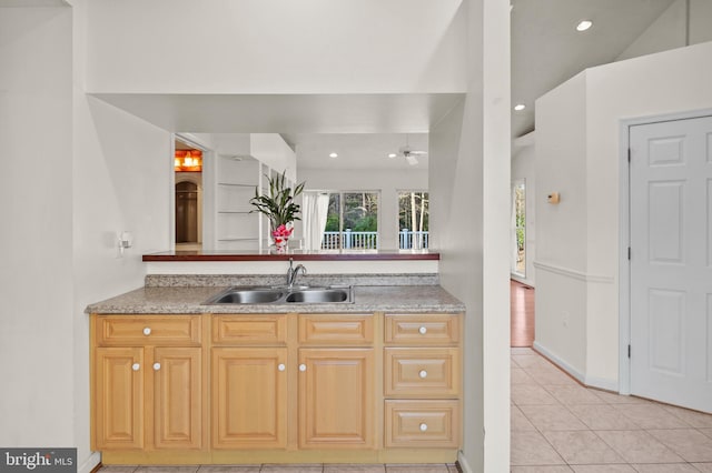 kitchen featuring baseboards, light countertops, light tile patterned floors, recessed lighting, and a sink