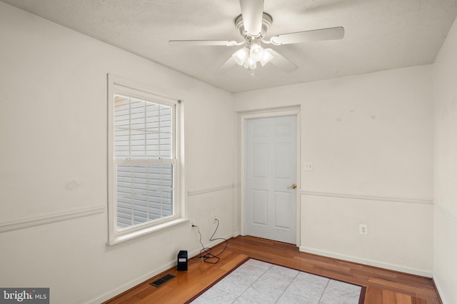 unfurnished room with baseboards, wood finished floors, visible vents, and ceiling fan