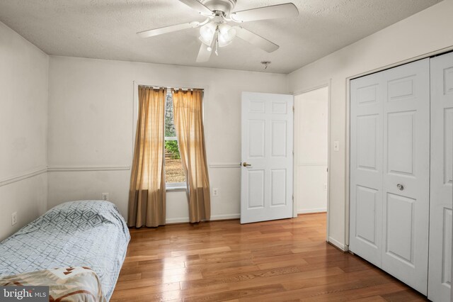 bedroom with a textured ceiling, wood finished floors, and a ceiling fan