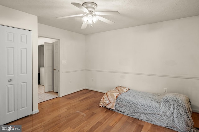 bedroom featuring a ceiling fan, wood finished floors, and a textured ceiling