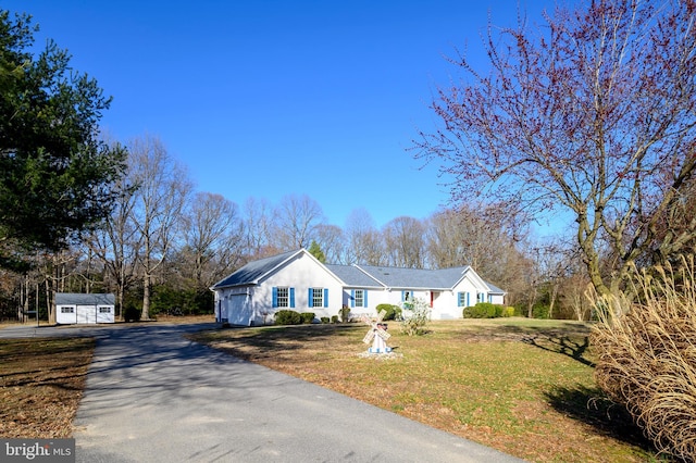 view of front facade featuring a garage, an outdoor structure, and a front lawn