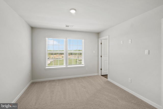 carpeted spare room featuring visible vents and baseboards