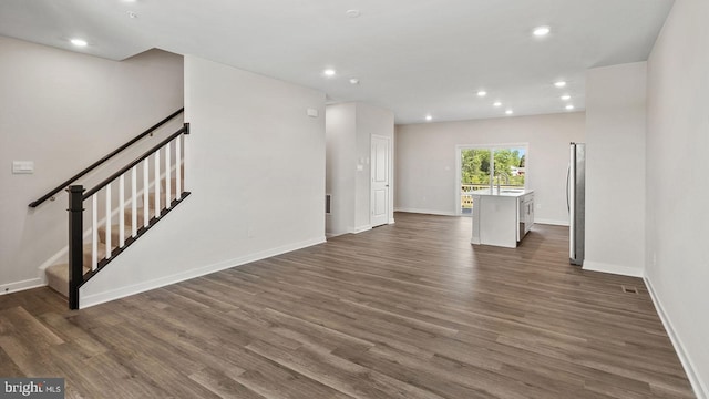 unfurnished living room featuring stairs, dark wood-type flooring, baseboards, and recessed lighting