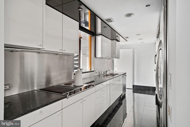 kitchen with white cabinets, stainless steel electric stovetop, a sink, and dark tile patterned floors