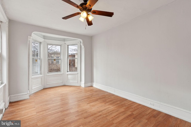 unfurnished room featuring light wood-type flooring, baseboards, and a ceiling fan