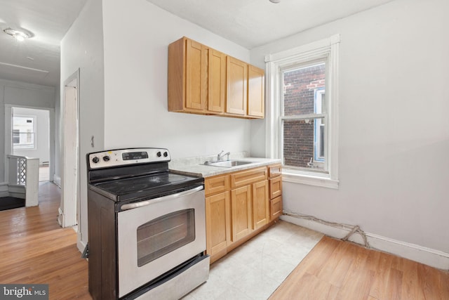 kitchen with light brown cabinets, electric stove, a sink, and light countertops