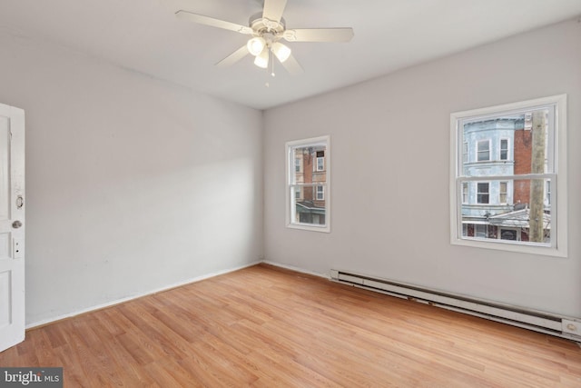 spare room with ceiling fan, light wood finished floors, and baseboard heating