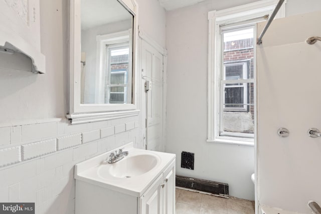 bathroom with a wealth of natural light, tile patterned flooring, vanity, and tile walls