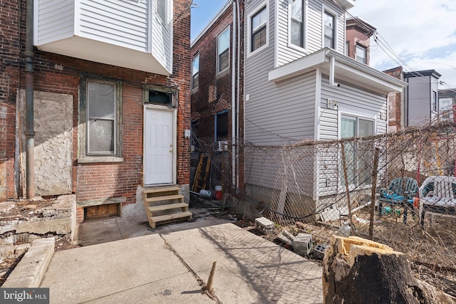 exterior space with entry steps, fence, and brick siding