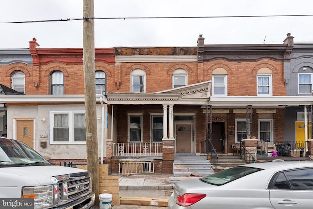 view of property featuring a porch and brick siding