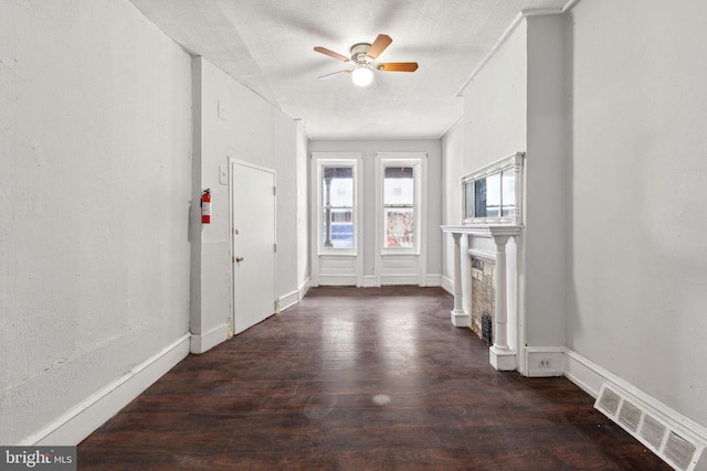 entrance foyer with ceiling fan, a fireplace, wood finished floors, visible vents, and baseboards